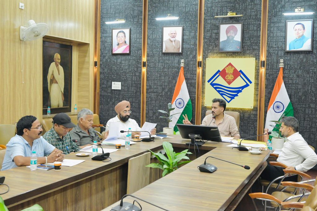 देहरादून के DM एक कॉन्फ्रेंस टेबल के चारों ओर राजनीतिक दलों के एजेंटों के साथ बैठक कर रहे हैं।